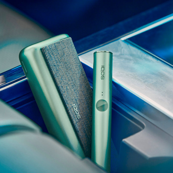A Jade Green IQOS ILUMA PRIME Holder and Pocket Charger in a person's hands.